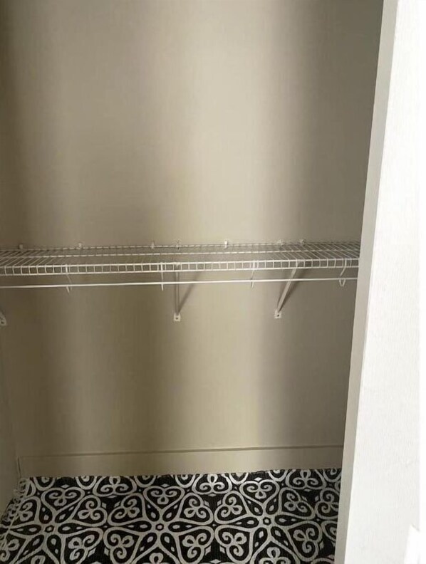 A closet with two metal shelves and a patterned rug on the floor. - The Townhouse in Dayton- Close to UD (Dayton)