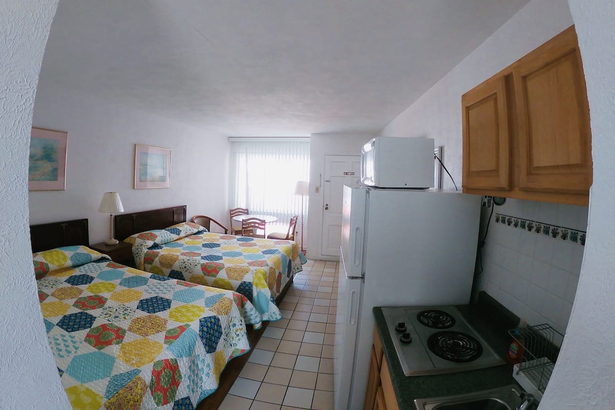 Une chambre d’hôtel compacte comprenant deux lits, une kitchenette, un coin repas et une salle de bain.