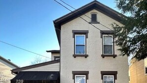 A two-story building with a beige facade, a black awning, and a number '239' on the side. - Farmhouse in the City (Dayton)