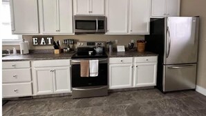 A kitchen with white cabinets, stainless steel appliances, and a marble countertop. - Farmhouse in the City (Dayton)