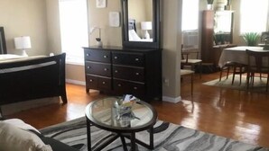 Un salon avec un canapé, une table basse, une commode sombre et un ventilateur de plafond.
