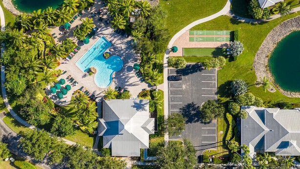 Vista aérea de um resort com piscina central, várias quadras de tênis e estacionamento.