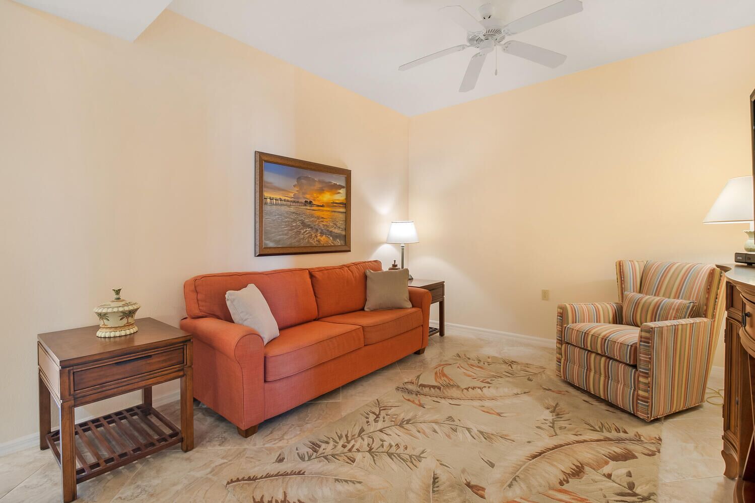 A living room with a sofa, a chair, a lamp, a painting, and a decorative table.