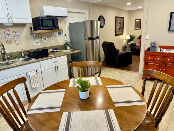 A modern kitchen with white cabinets, a stainless steel refrigerator, a microwave, and a coffee station.