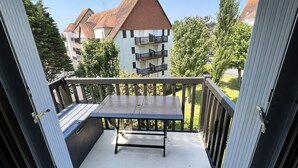 A balcony with a table and chairs, overlooking a residential area with houses and trees. - Charming cocoon (Cabourg)