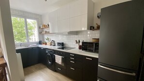 A modern kitchen with a built-in washing machine, a microwave, and a refrigerator. - Cosy, calme et lumineux à Paris Bastille - 2mn du métro (Paris)
