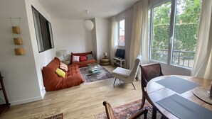 A modern living room with a sofa set, a dining table, and a TV. - Cosy, calme et lumineux à Paris Bastille - 2mn du métro (Paris)