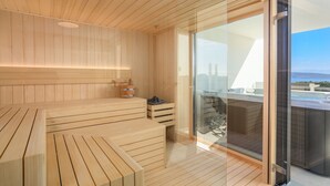 Een moderne sauna met houten banken en een glazen deur die uitkomt op een balkon met uitzicht.
