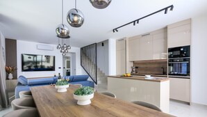 Een moderne keuken met een centraal eiland, inbouwapparatuur en een trap naar een hoger gelegen verdieping.