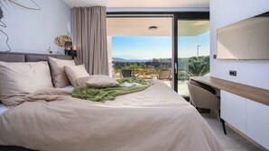 Een moderne hotelkamer met een groot bed, een bureau en uitzicht op het landschap.