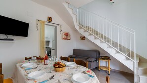 Ein Essbereich mit einem Tisch für vier Personen, einer Couch und einer Treppe.