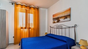 Ein Schlafzimmer mit einem Bett, Vorhängen, einer Lampe und einem Bild an der Wand.