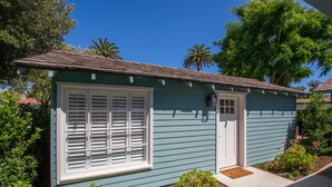 A small, single-story house with a light blue exterior, a white front door, and a window with white shutters. - Studio Bella - Solvang, CA (Solvang)