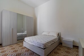 Ein Schlafzimmer mit einem Bett, einem Kleiderschrank, einem Nachttisch und einem Boden mit Muster.
