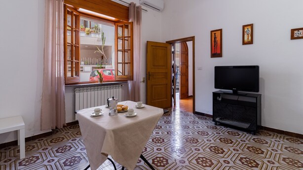 A room with a table set for two, a television, and a window with curtains.