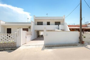 Stunning two-story building with a symmetrical facade, featuring a decorative entrance gate and a flat roof.