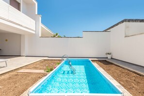 Relax by the pool surrounded by lush greenery and a clear blue water surface.