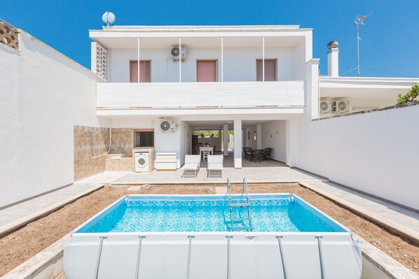 Enjoy a refreshing swim in the pool surrounded by a spacious outdoor area with a covered patio above.