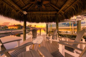 Relax on the waterfront deck with Adirondack chairs and a small table, surrounded by calm waters and a serene shoreline.
