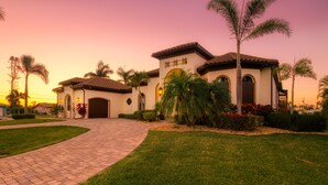 A two-story house with a tiled roof, a paved driveway, and a well-maintained lawn. - Intervillas Florida - Bella Villa 141 (Cape Coral)
