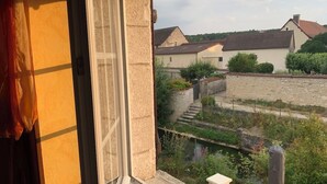 A view from a window overlooking a garden with a small water feature and a stone wall.