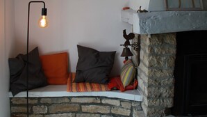 A stone fireplace with a white mantel, a wall-mounted light fixture, and a bench with cushions.