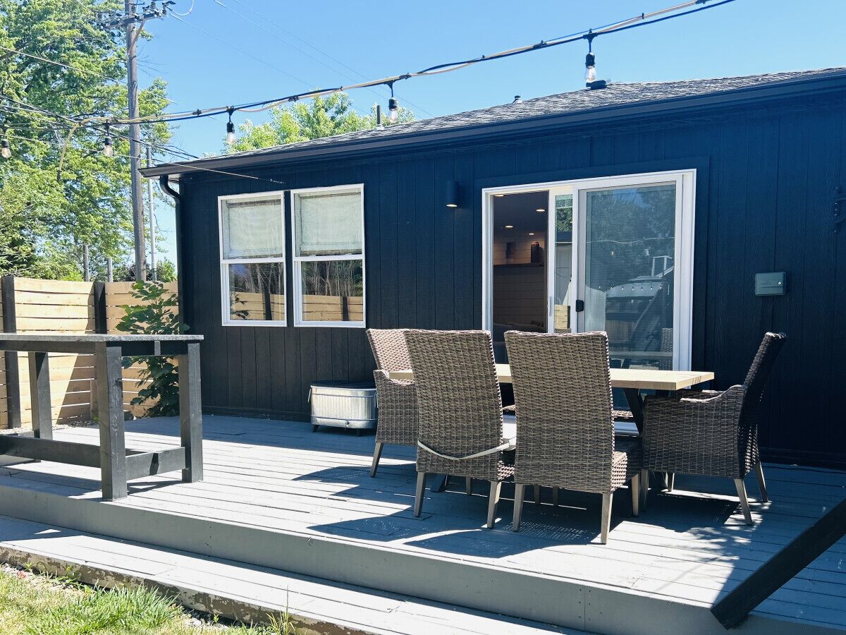 An outdoor deck with wicker furniture, a table, and a bench.