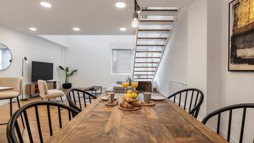 Een moderne eetruimte met een houten tafel, zwarte stoelen en een trap op de achtergrond.