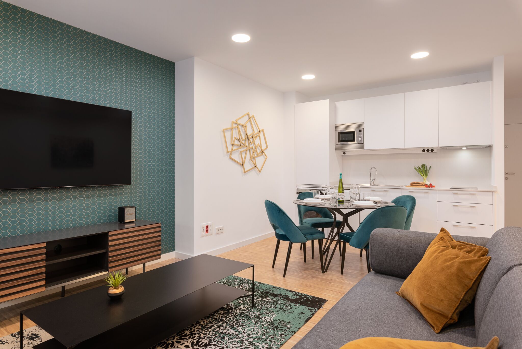 Una sala de estar moderna con televisor de pantalla plana, un sofá, una mesa de centro y un comedor con sillas y una mesa.