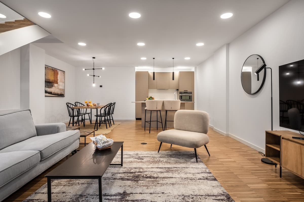 A modern living room with a sofa, coffee table, and a dining area with chairs and a table.