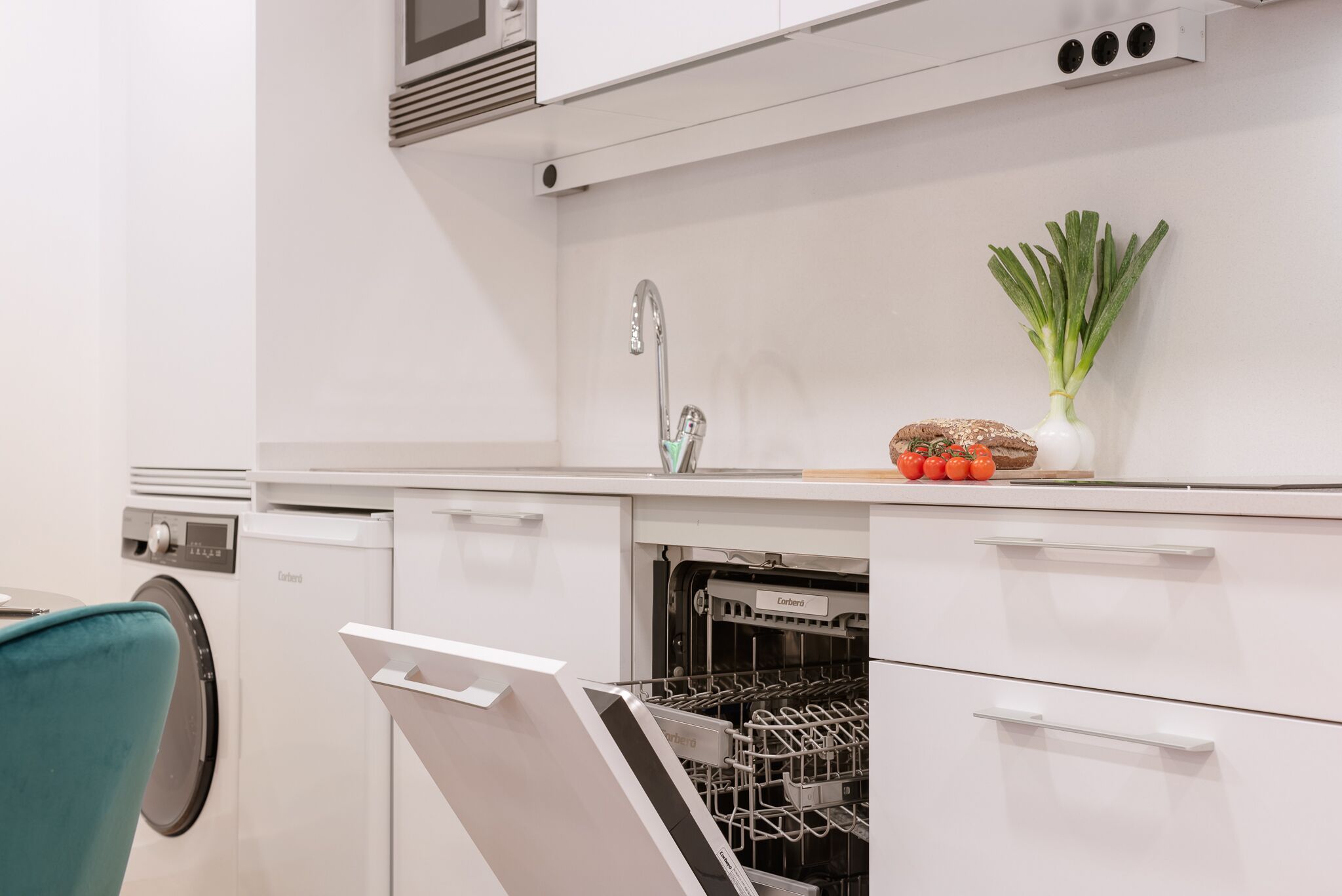 Una cocina moderna con armarios blancos, lavavajillas y pileta.