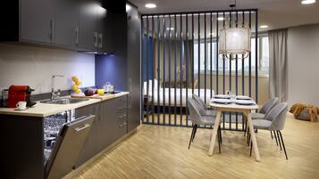 A modern kitchen with a dishwasher, a coffee machine, and a dining area with a table and chairs.