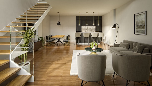 A spacious living area with a high ceiling, a staircase leading to an upper level, and a kitchen area in the background.