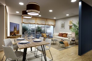 A modern dining area with a wooden table, chairs, and a view of the cityscape through large windows.