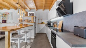 A modern kitchen with wooden beams, white cabinets, and a bar area with stools. - Lavova in Brtonigla With 3 Bedrooms and 2 Bathrooms (Brtonigla)