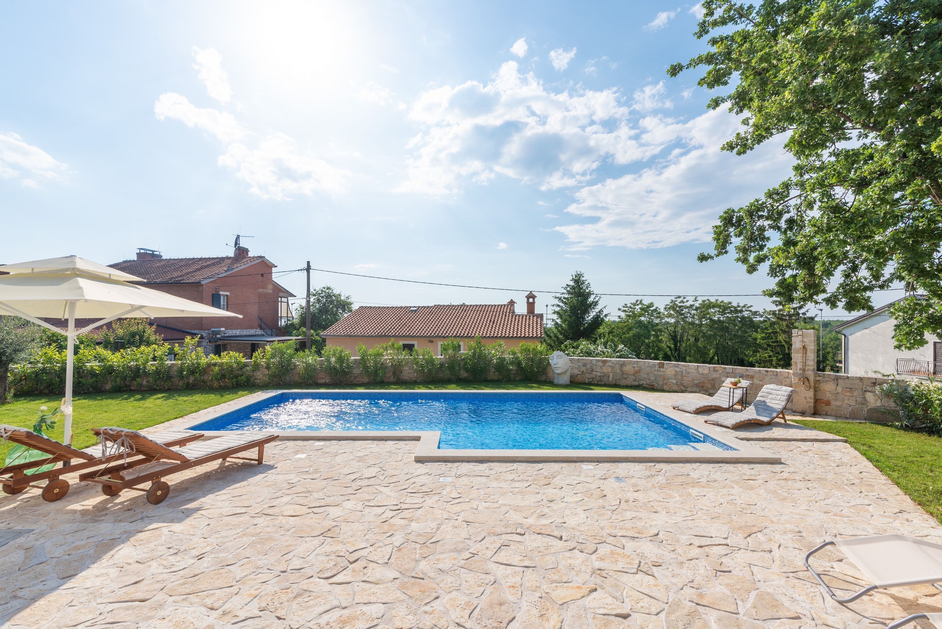 A swimming pool with lounge chairs and a stone patio.