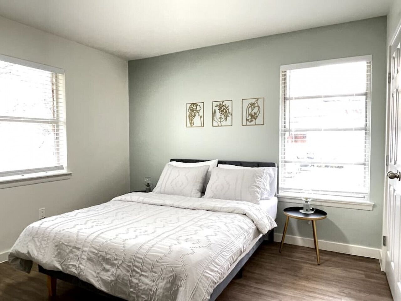 Ett sovrum med en säng, sängbord och tre konstverk som hänger på väggen.