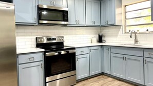 Une cuisine moderne avec des meubles bleu clair, des appareils en acier inoxydable et des carreaux de métro blancs.
