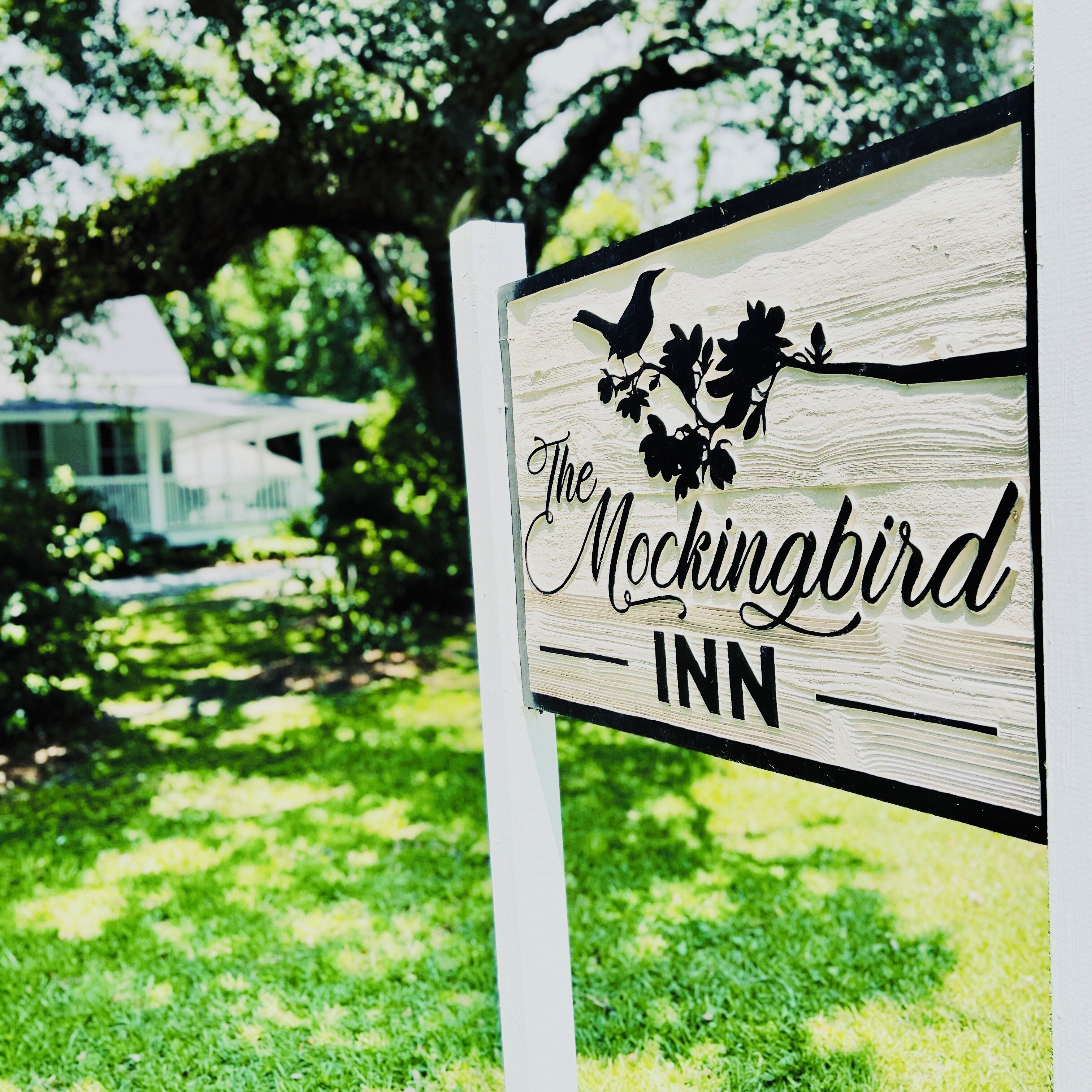 A wooden sign with the text "The Mockingbird Inn" and a bird silhouette.