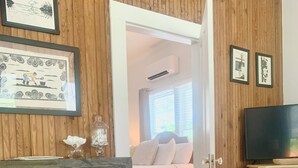 A bedroom with a bed, a TV, and a wooden wall. - Willow Suite at The Mockingbird Inn Boutique Hotel (Ocean Springs)
