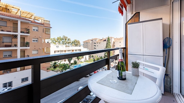 Ein Balkon mit Tisch, einer Weinflasche und einem Glas.