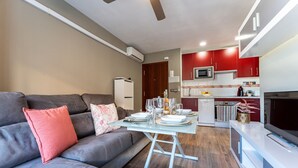 Ein modernes Wohnzimmer mit grauem Sofa, einem Glastisch und einem Essbereich für vier Personen.