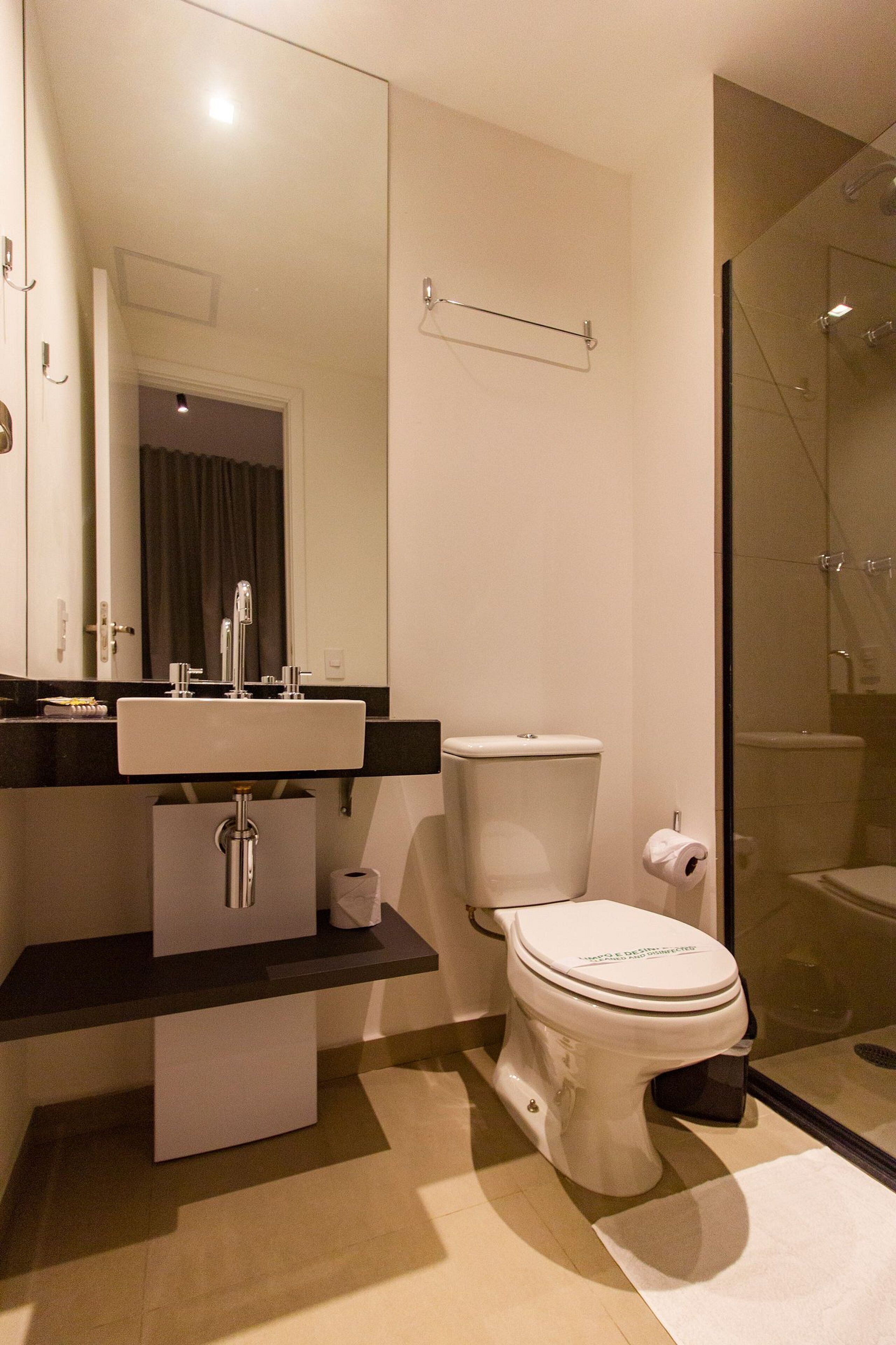 A modern bathroom with a white sink, toilet, and shower.