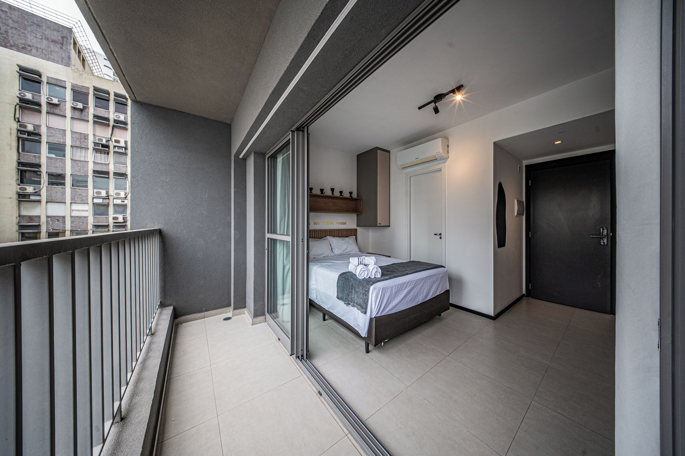 Habitación de hotel con cama, puerta, ventana y balcón.