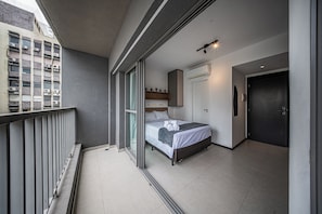 A hotel room with a bed, a door, a window, and a balcony. - VN Consolação (São Paulo)