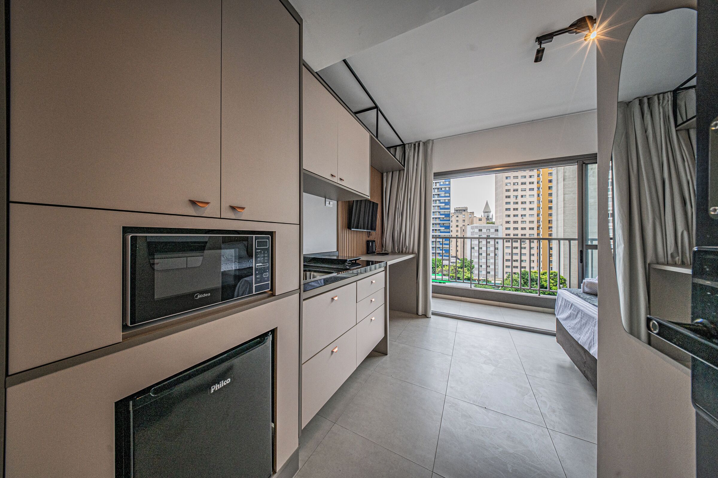 A modern kitchen with a built-in oven, microwave, and a large window offering a city view.