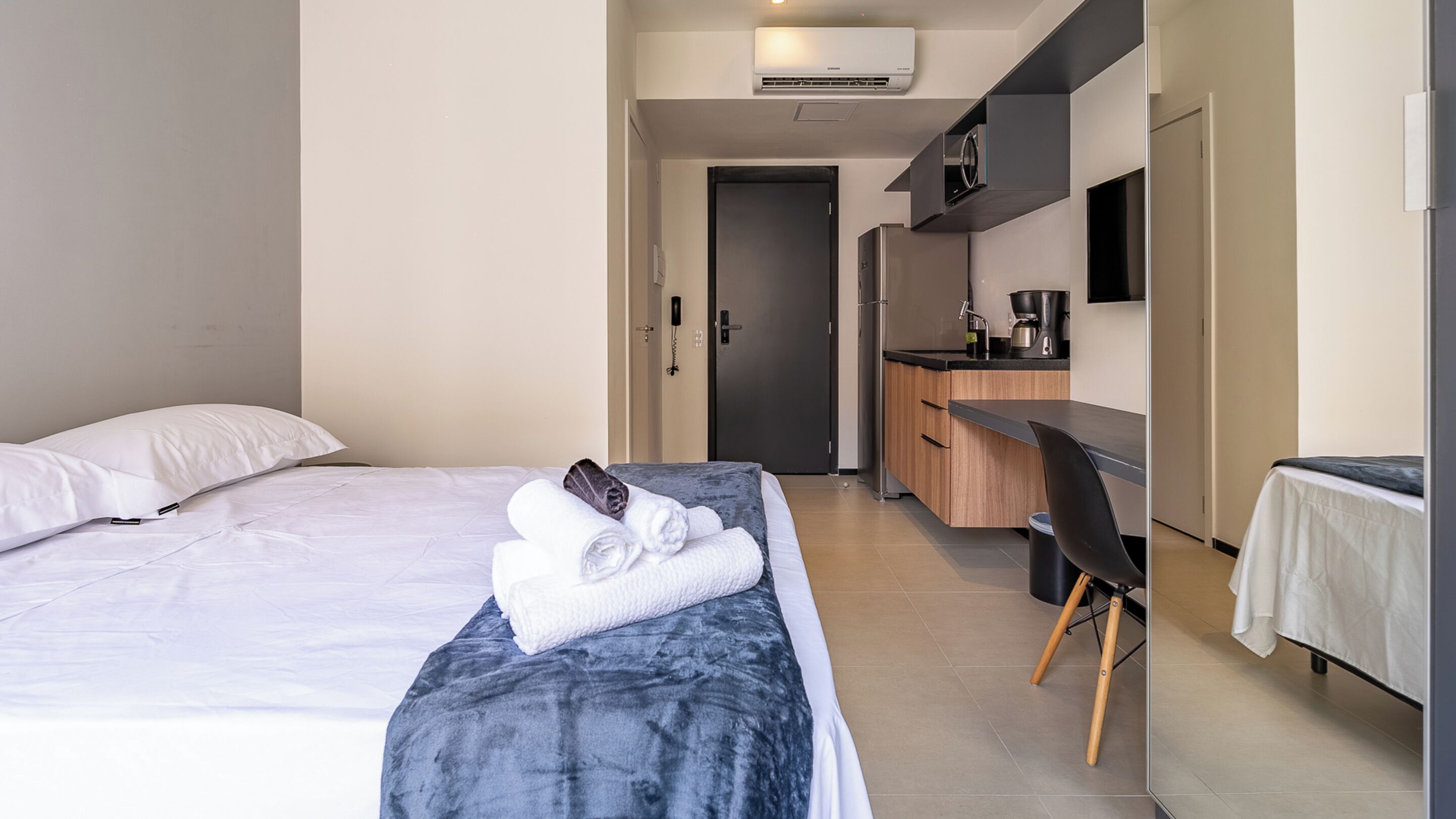 Une chambre d’hôtel équipée d’un lit, d’un bureau, d’une chaise et d’une kitchenette.