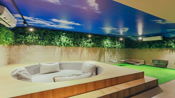 Un moderno espacio de spa con un jacuzzi, una silla colgante y una camilla de masaje.