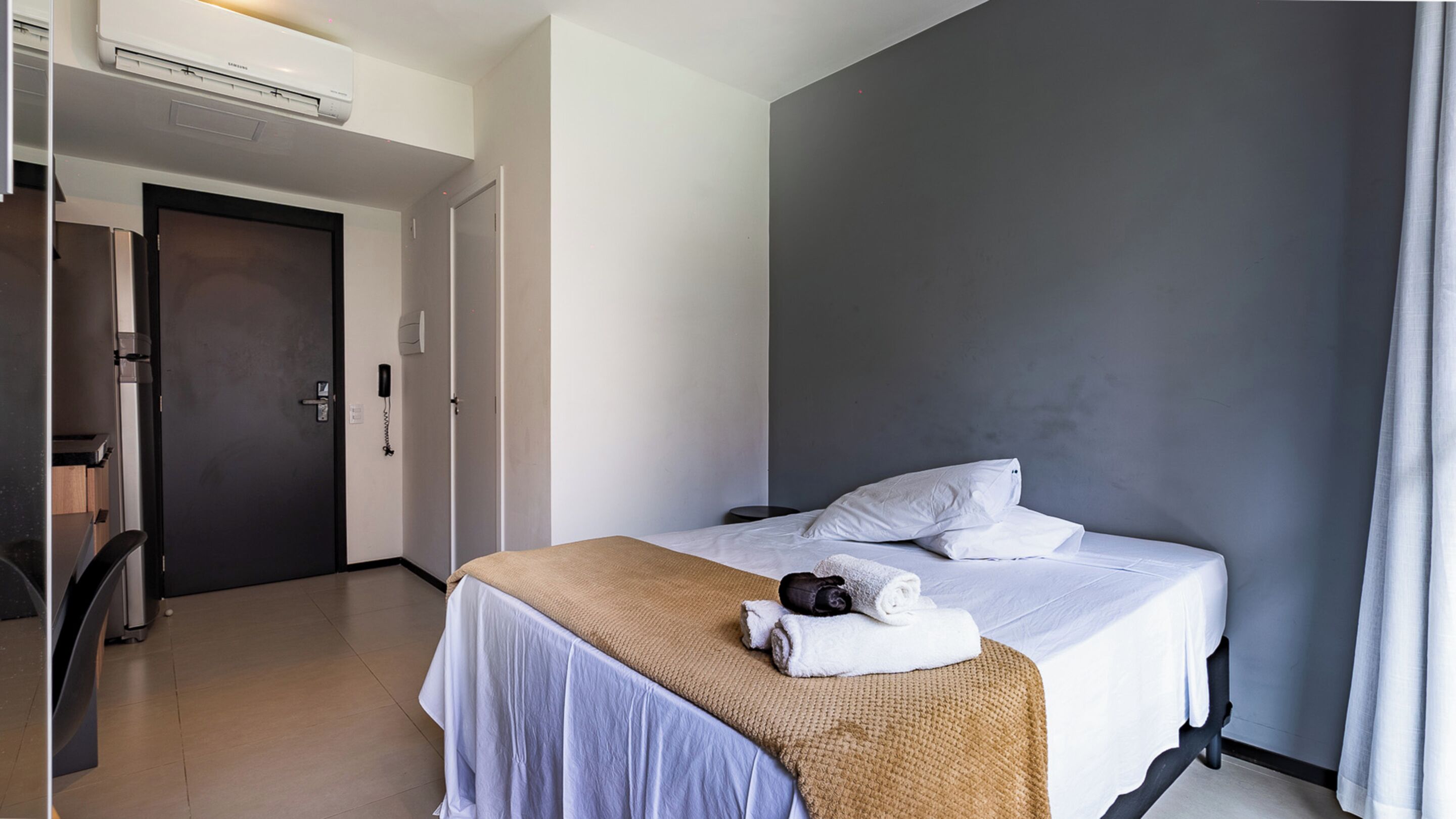 Une chambre d’hôtel équipée d’un lit, d’une table de chevet, d’un téléphone et d’un appareil de climatisation.