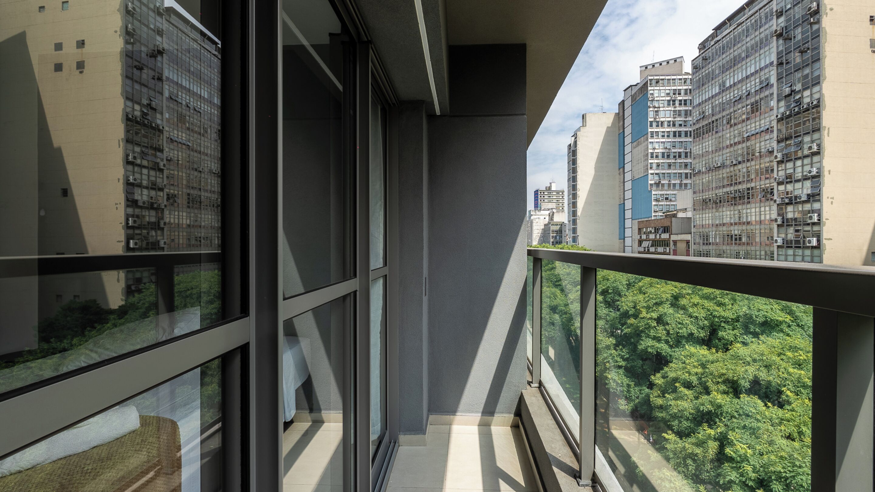 Un balcón con vistas a vegetación exuberante y edificios altos.